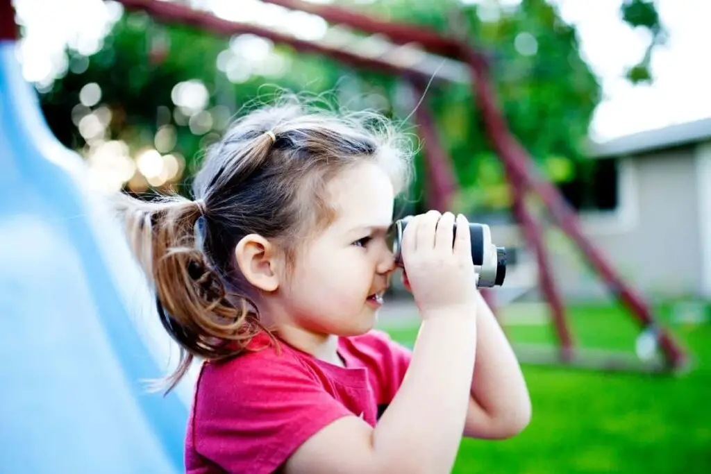 a little girl using binoculars to watch birds