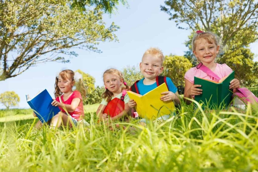 four children reading outside