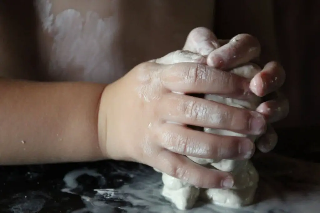 close up of a child's hands making something with clay