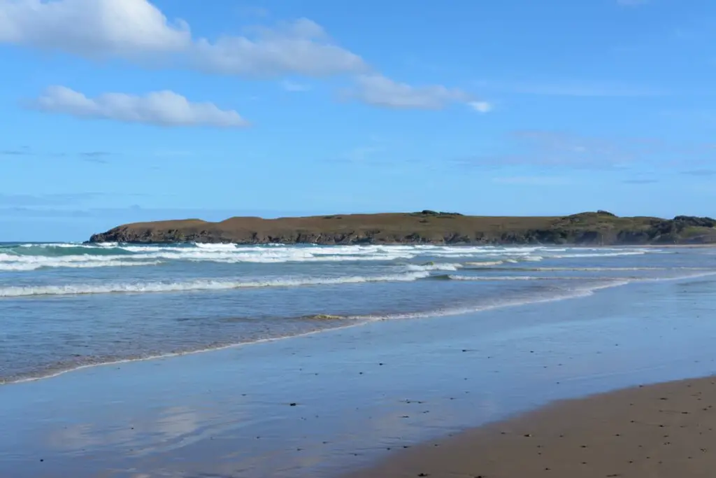 a beach with a rocky headland in the background