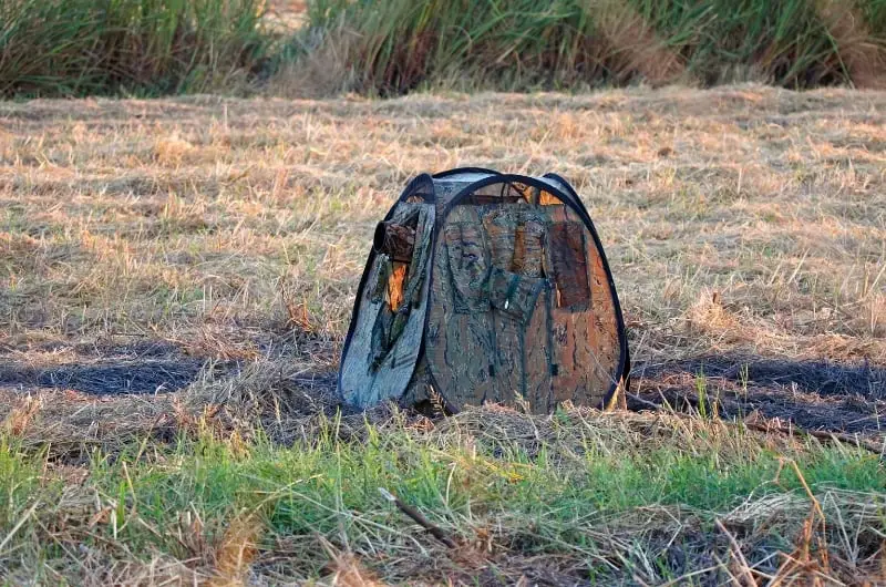 a portable camouflage bird hide set up in a field