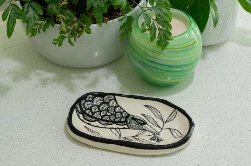 a ceramic plate with a hand-painted magpie picture on it