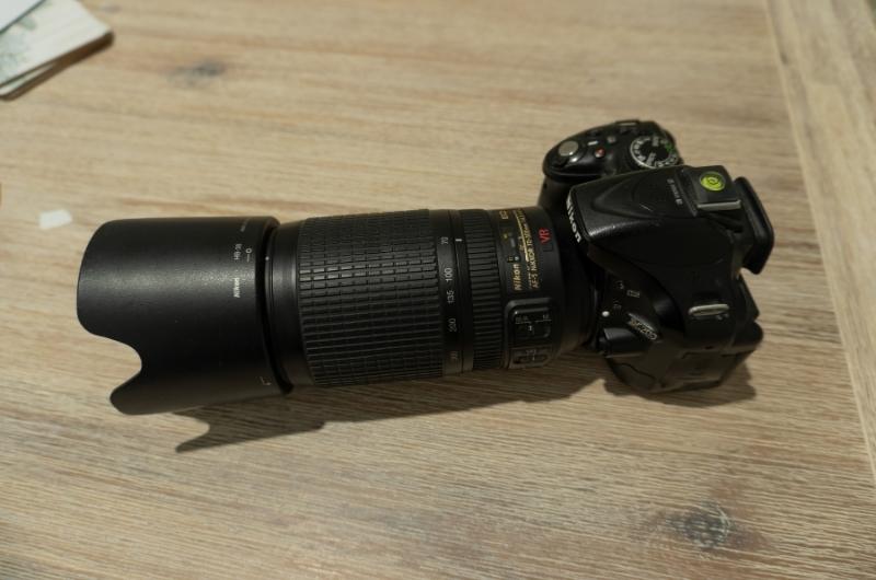 a Nikon D5200 DSLR camera with a 70-300mm lens attached sitting on a wooden table