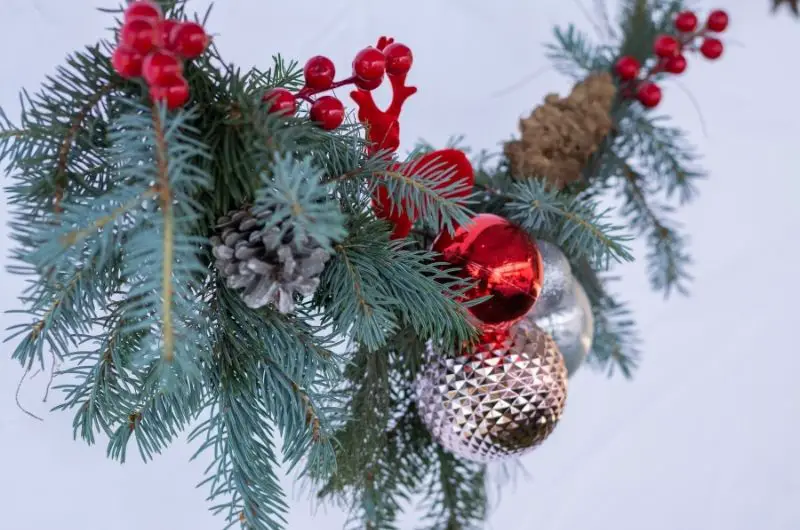 red and silver Christmas decorations hanging from a string of pine