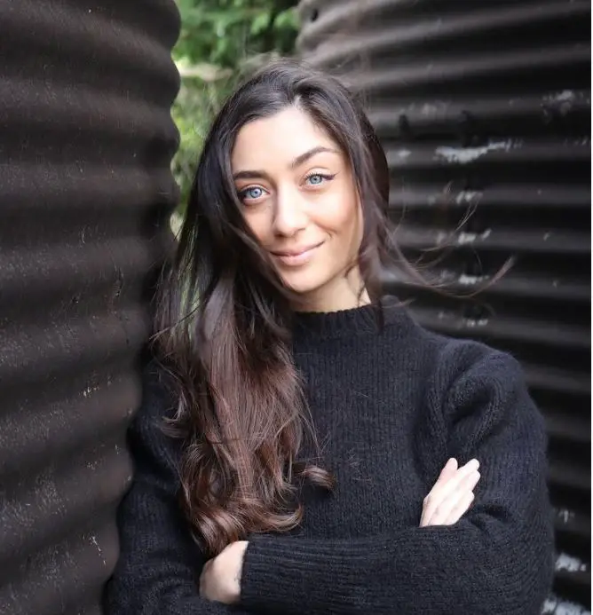 Taxidermist Elle Kaye leaning against a corrugated iron tank