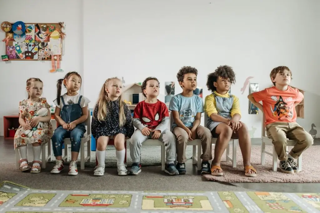 seven preschool children sitting on chairs