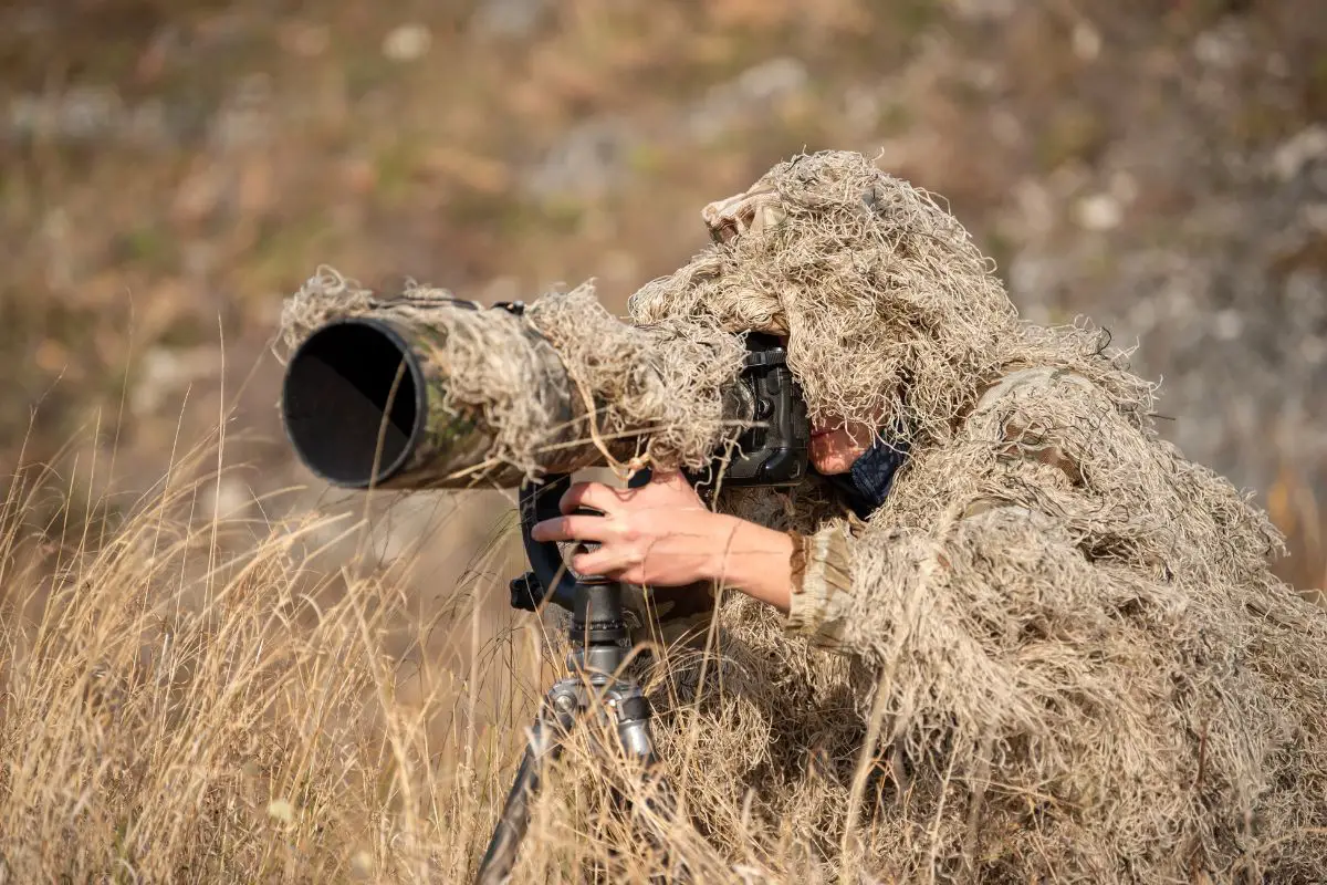 a wildlife photographer in a camouflage suit