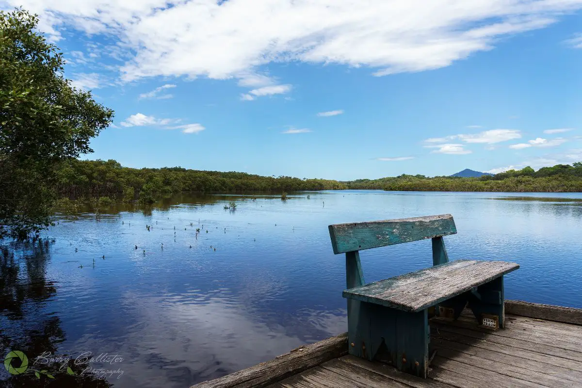 a view of Urunga Lagoon in New South Wales Australia with a wooden seat in the foreground