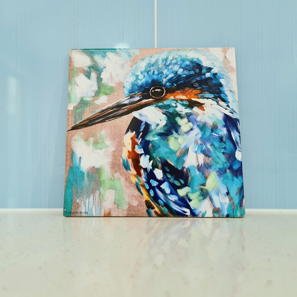 a trivet with a hand-painted image of a Kingfisher on it