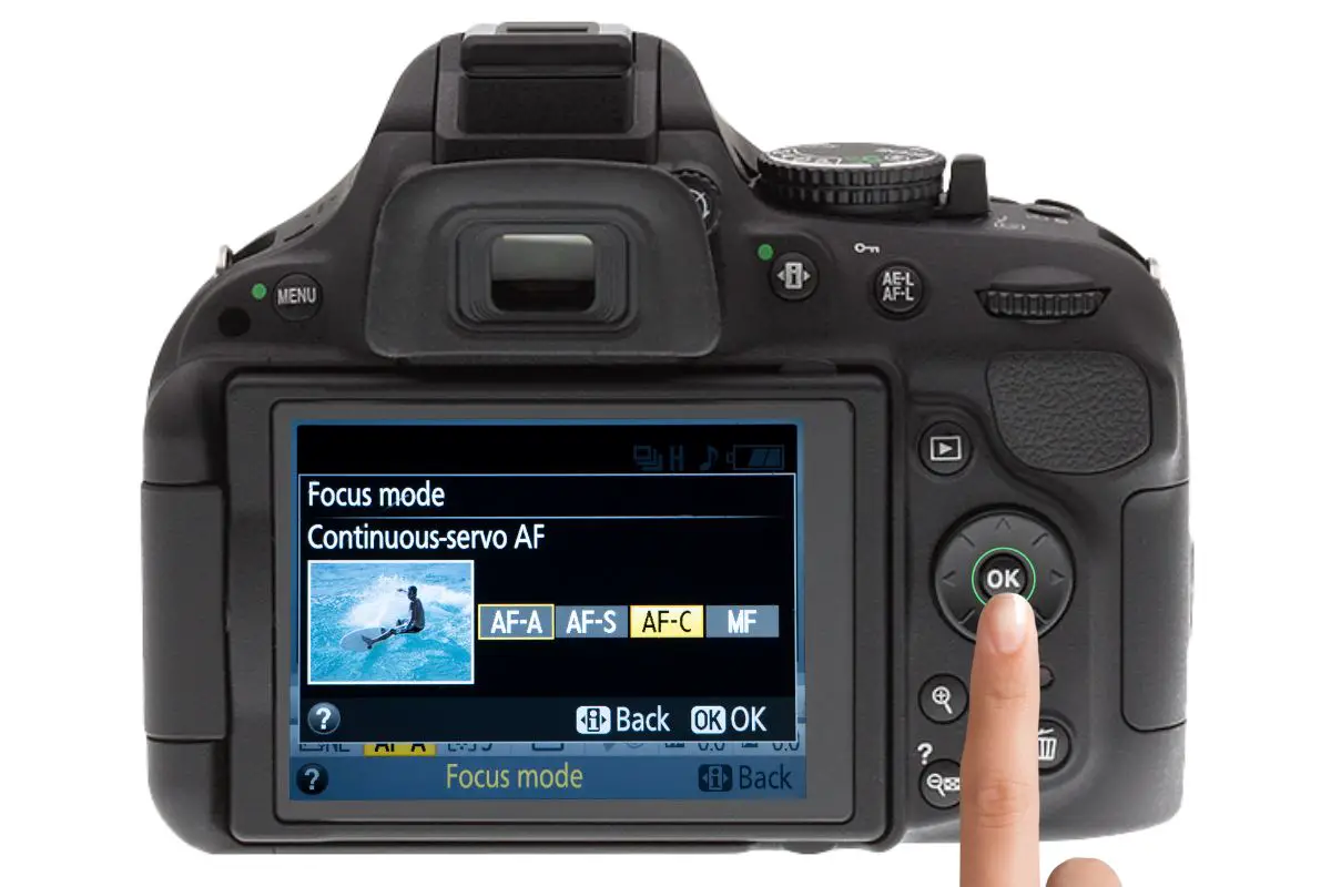 the rear of a Nikon D5200 showing the focus mode display with AF-C lit up. A woman's hand is pressing the ok switch