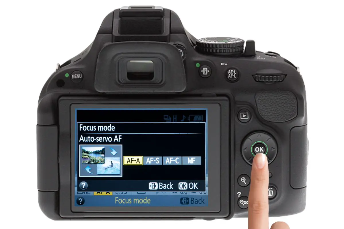 the rear of a Nikon D5200 showing the focus mode display. A woman's hand is pressing the ok switch