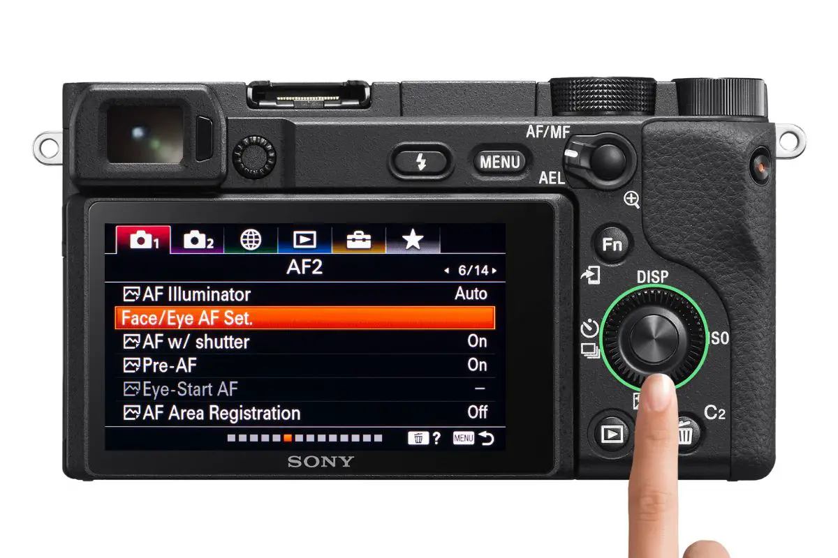 the rear of a Sony a6400 camera showing the AF2 screen with a woman's hand pressing the control wheel