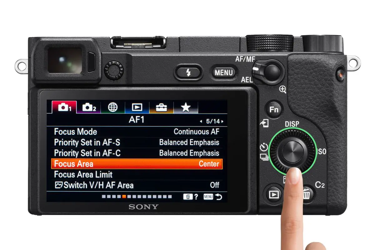 the rear of a Sony a6400 camera showing the AF1 screen with a woman's hand pressing the control wheel