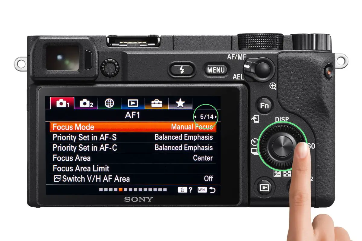 the rear of a Sony a6400 camera showing the Focus Mode menu with a woman's hand pressing the control wheel