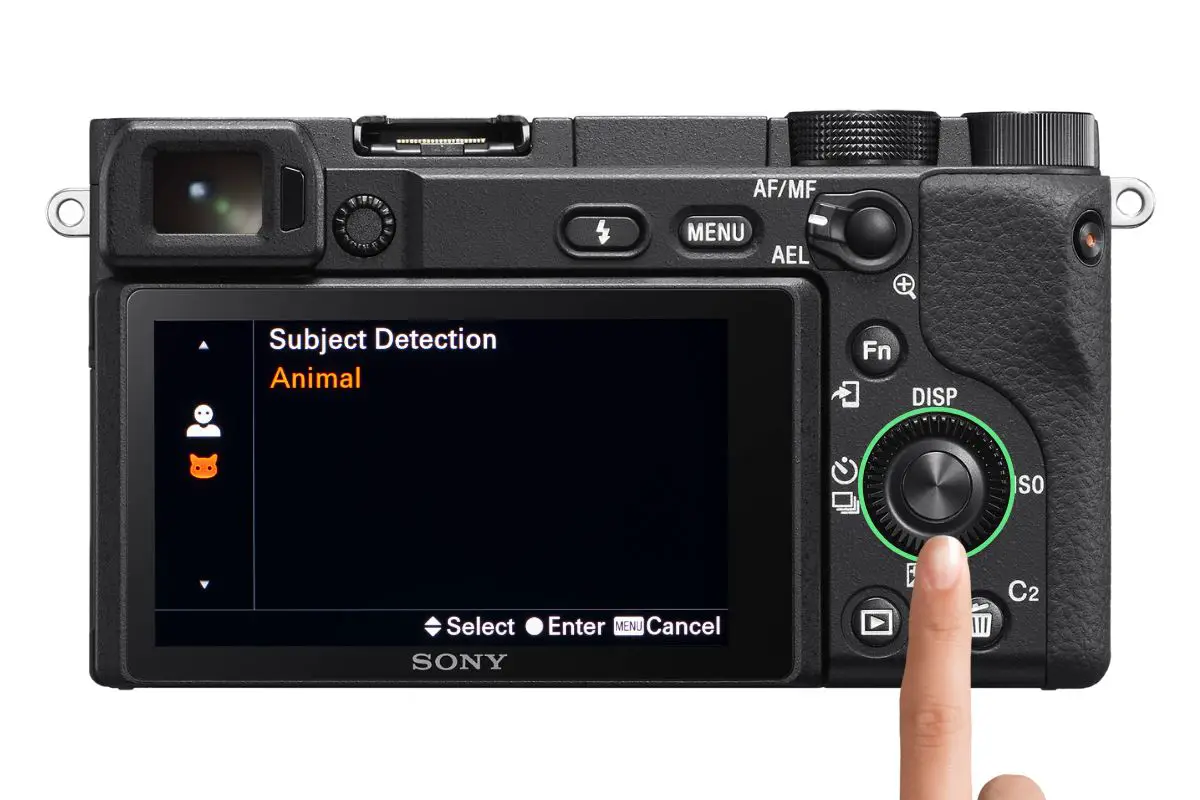 the rear of a Sony a6400 camera showing the Subject Detection screen with a woman's hand pressing the control wheel