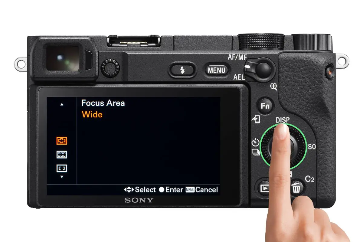 the rear of a Sony a6400 camera showing the Focus Area screen with a woman's hand pressing the control wheel