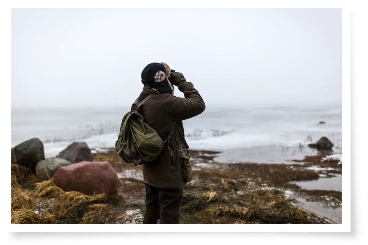 a man bird watching on the edge of a frozen sea