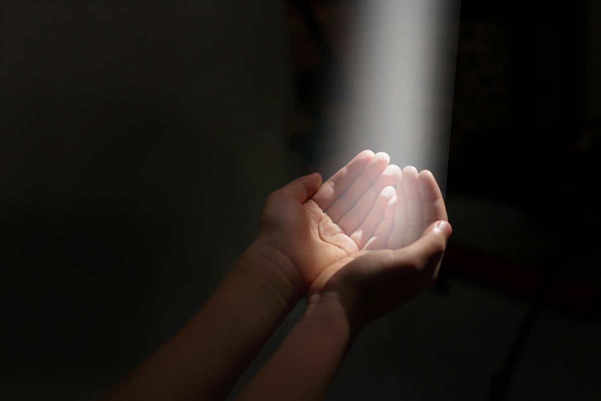 hands cupped under a beam of light