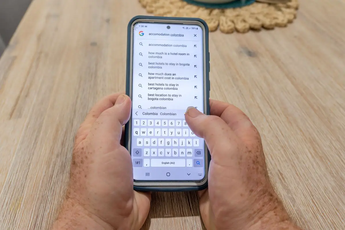 mans hands holding a smartphone with a Google search for accommodation Columbia on the screen